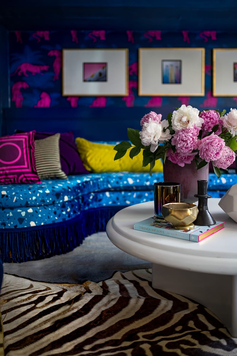 You have to see this amazing before and after transformation! I love the terrazzo blue sofa with blue fringe, the acid pink tiger wallpaper, zebra rug, chic living room and bright, bold color choices.