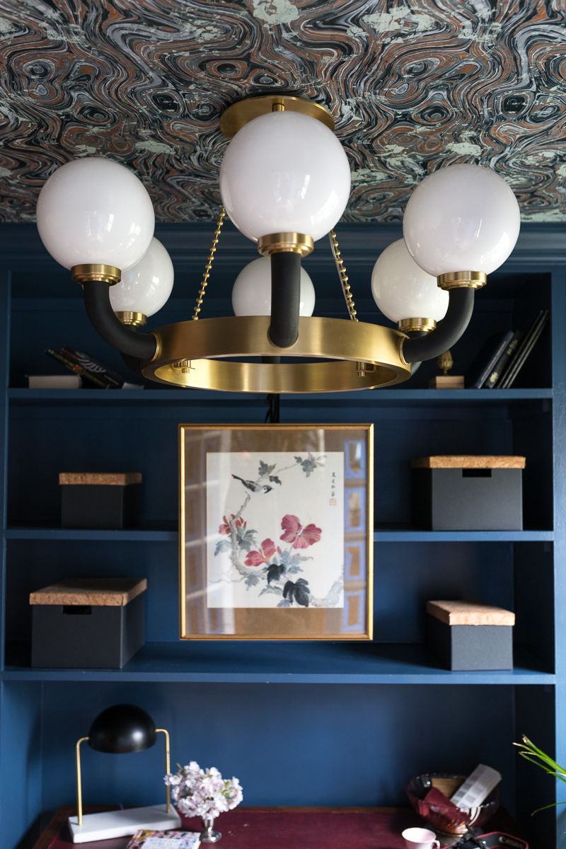 Jeweled Interiors Stiffkey Blue, Farrow and Ball, office, with built in shelves, and organization boxes, and antique desk and chair, wallpapered ceiling, oversized art