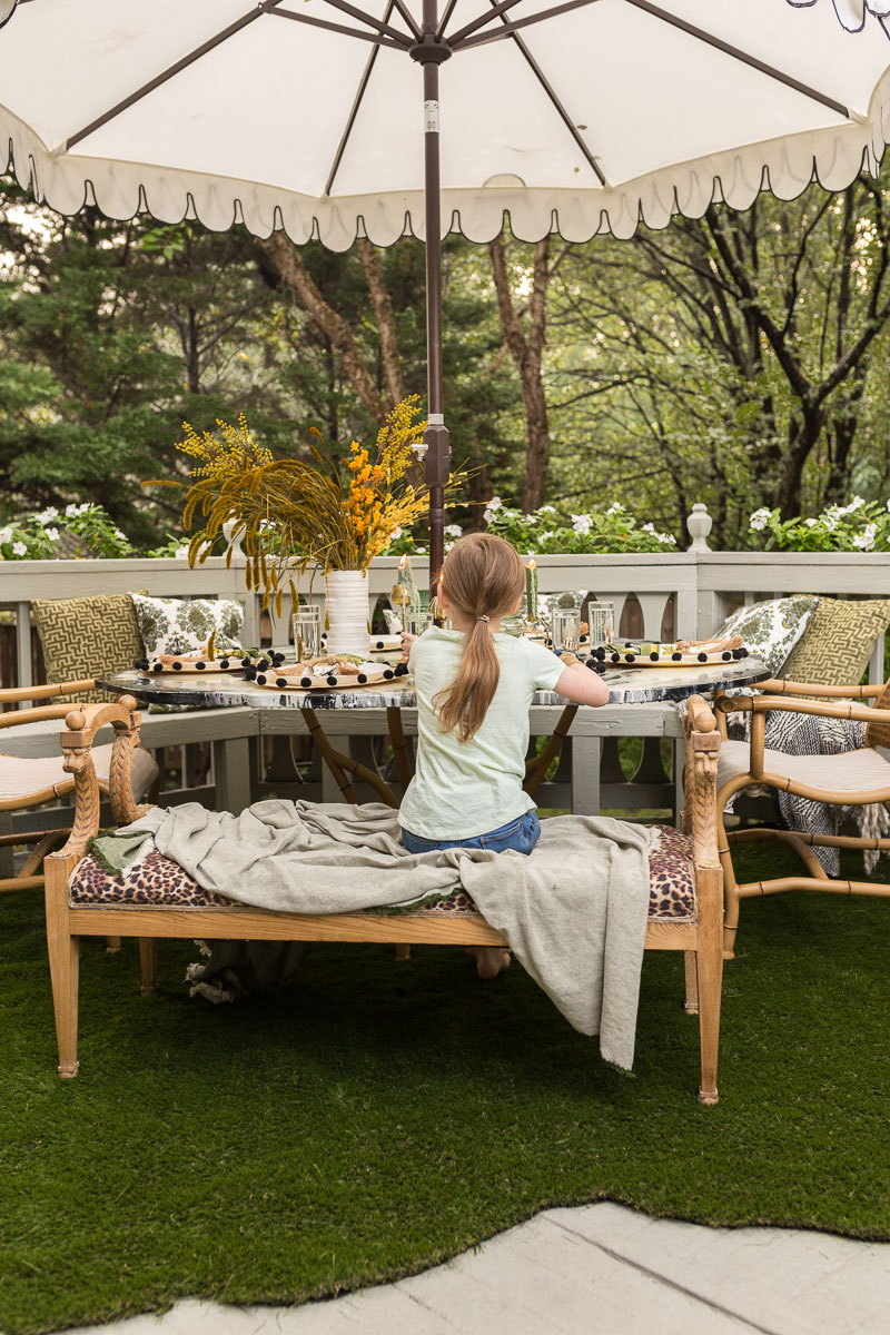 patio decorating ideas, patio ideas, artificial grass rug, antique bench, agate table, deck, entertaining, fall, bamboo chair, black and white umbrella 