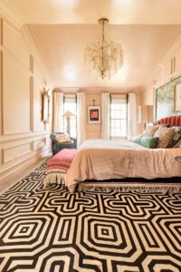 Elegant bedroom with patterned carpet and chandelier.